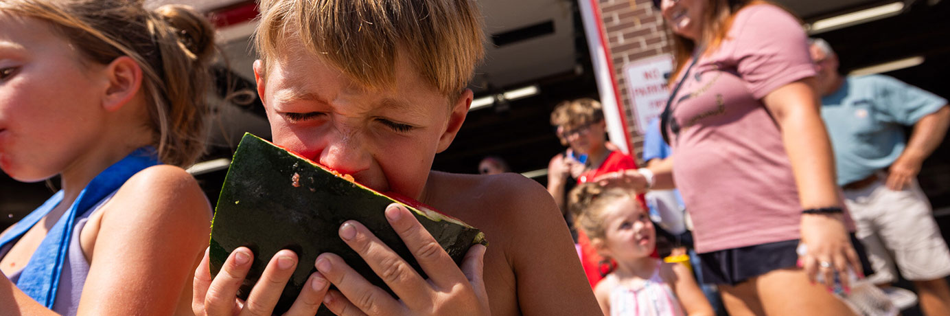 Boy eating watermelon at a fair