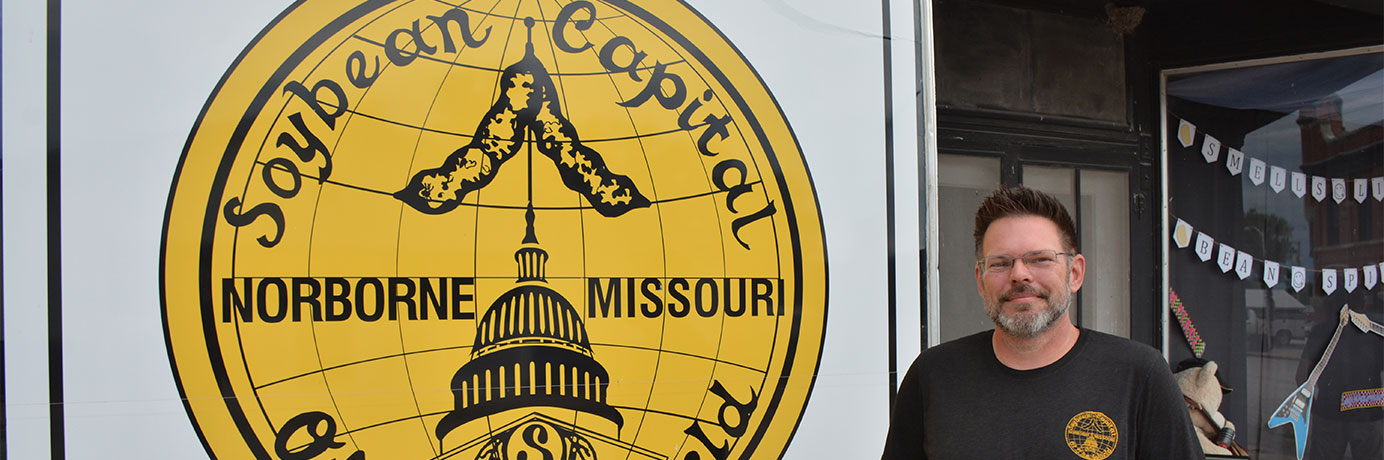 Man standing next to a large graphic that says Soybean capital of the world - Norborne, Missouri