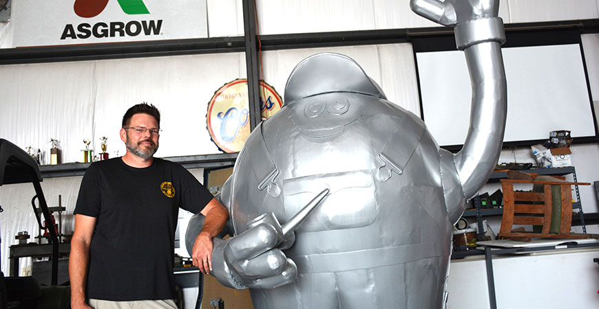 Kyle Durham, a member of the Norborne Soybean Festival Planning Committee, poses with Mr. Soybean, a sculpture the committee commissioned for the festival and community