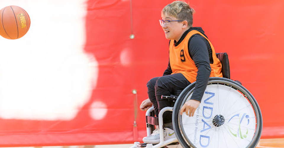 Boy playing basketball in a wheelchair