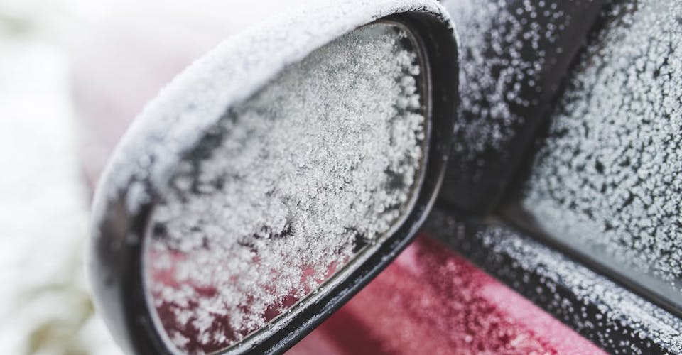 Car mirror and window covered in icy frost