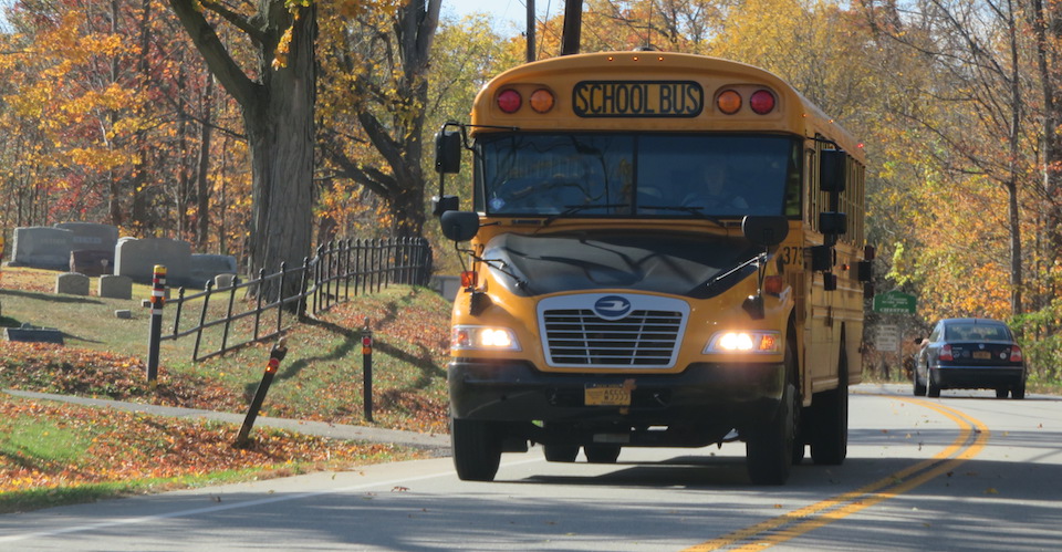 Propane auto-gas school bus driving down residential street.