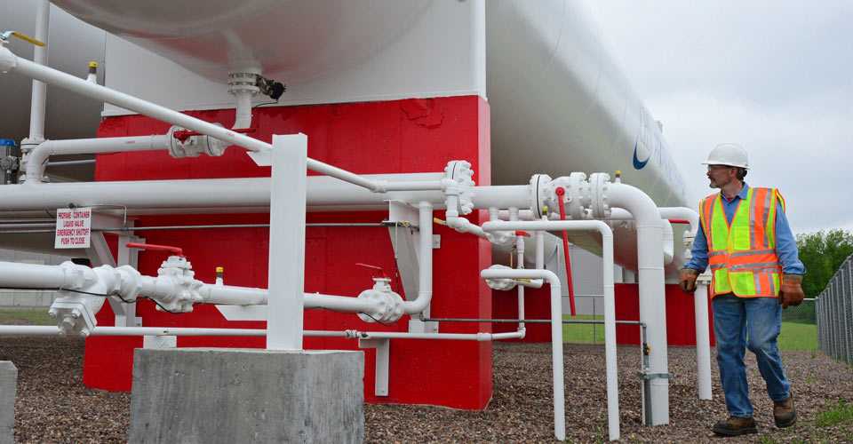 Man next to a large propane tank and pipelines