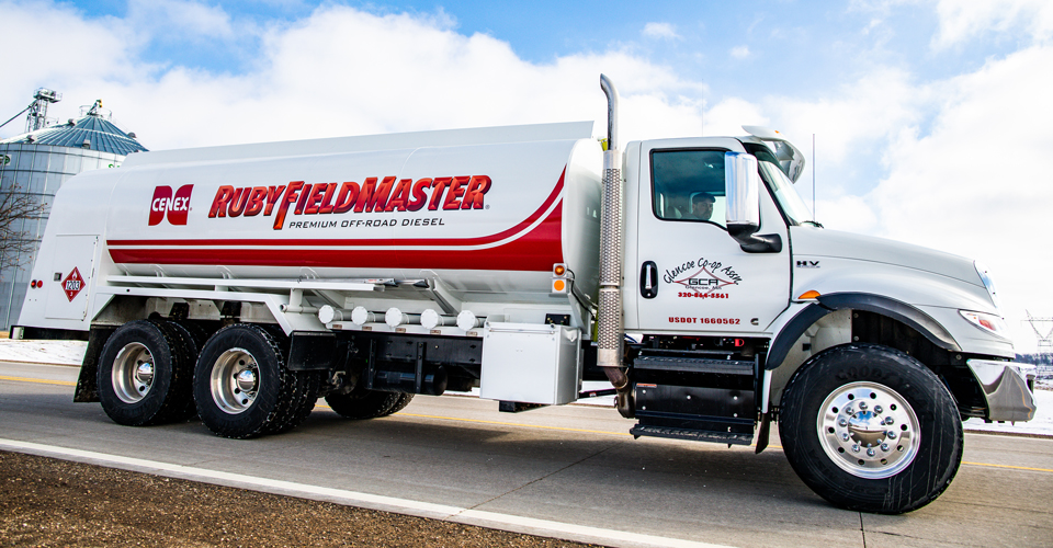Semi truck driving alongside field.