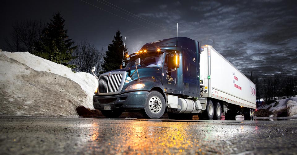 Semi truck parked at night in front of a snow pile
