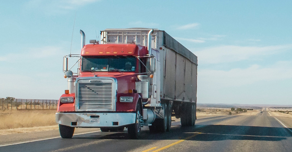 Semi truck driving down a flat, country road