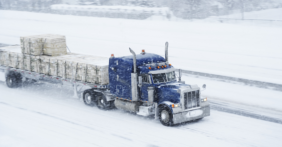 Semi hauling pallets of wood through a snowstorm