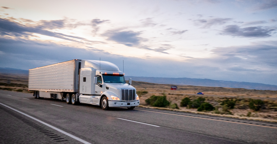Semi truck driving down a desert road