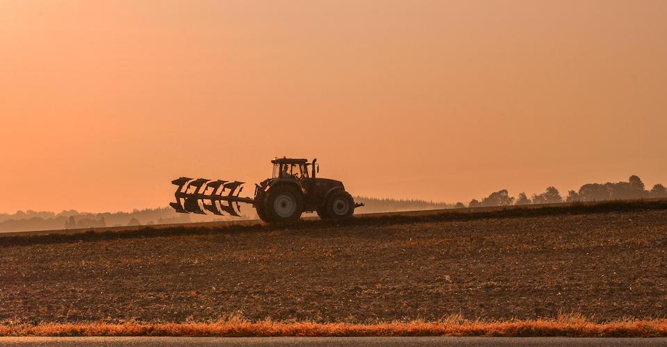 Tractor in a field at sunset
