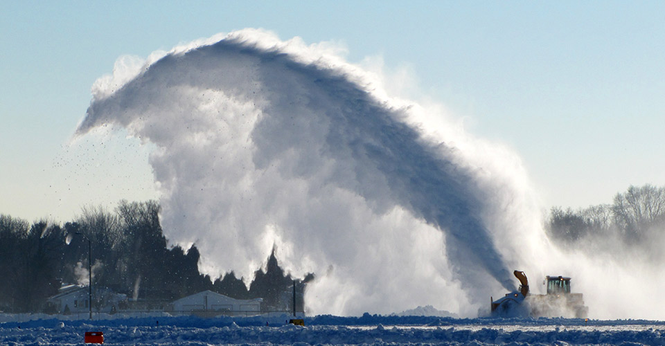 Tractor with snow blower blowing snow high into the air