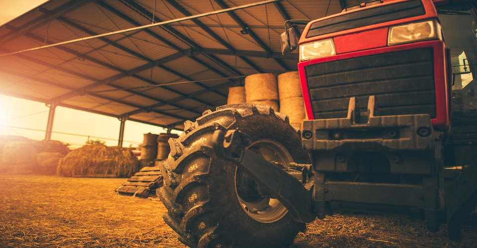 Tractor parked in a barn with a sunrise in the backyard