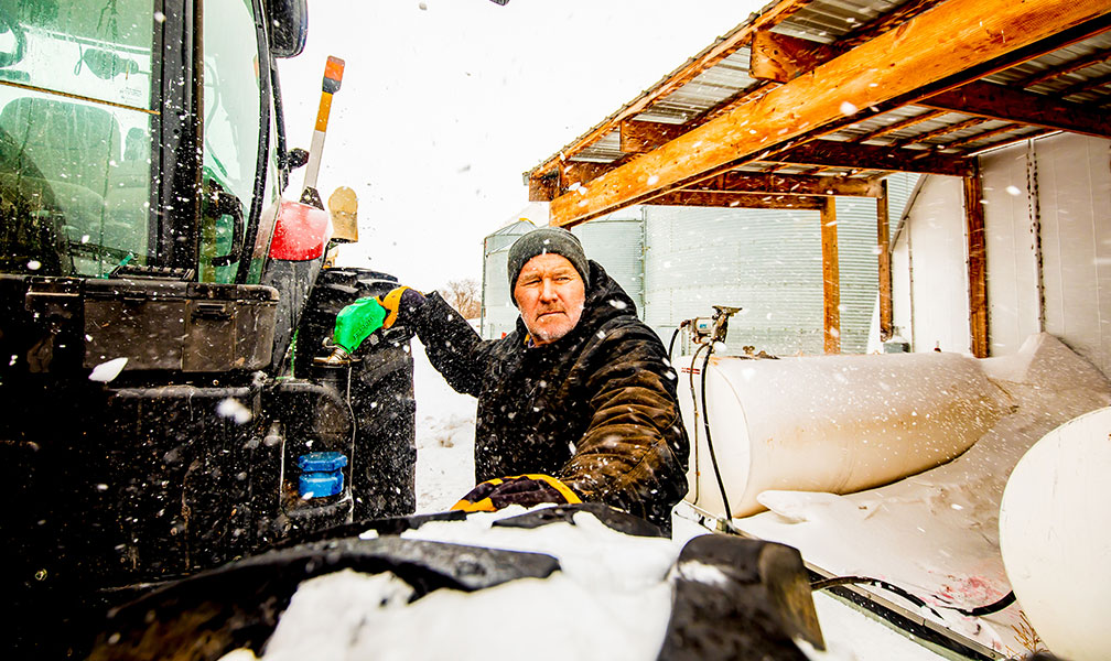 Man by his tractor in the snow